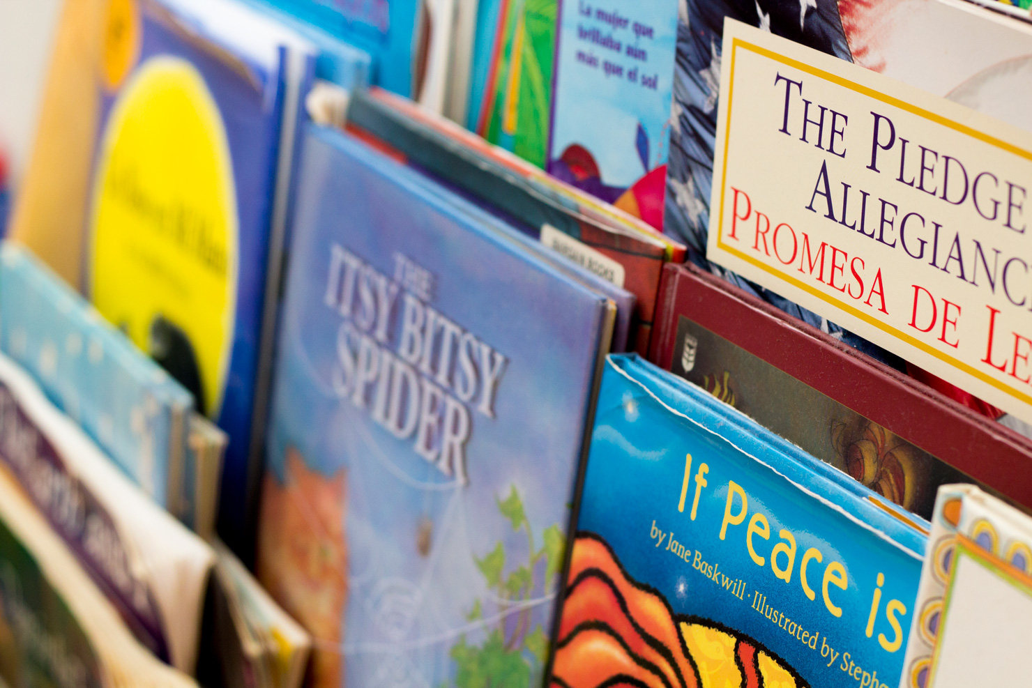 A shelf of picture books at Shining Stars, including bilingual English-Spanish titles, ready for story time.