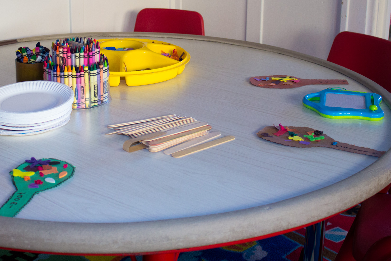 A closeup of crayon cups and popsicle sticks arranged on the art table at Shining Stars.